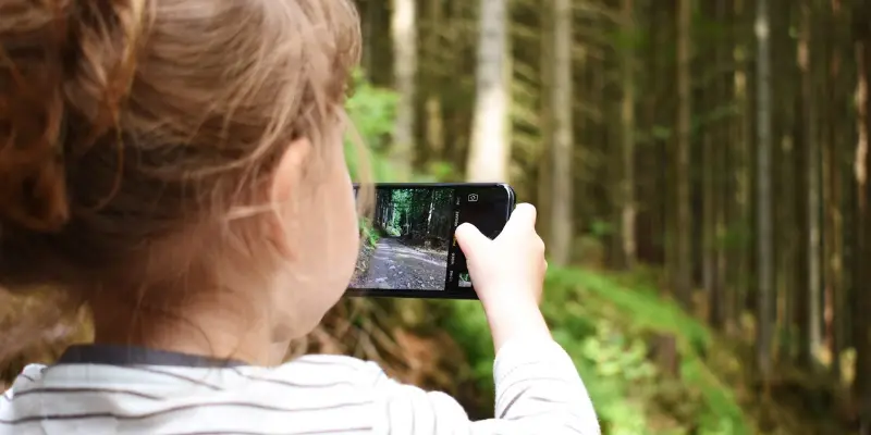 Neil Selwyn blog website image Photo of a young child in nature taking a picture on a smartphone